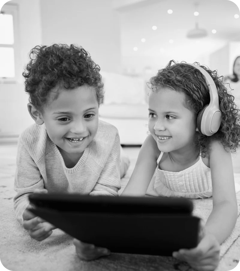 Two children with headphones using a tablet